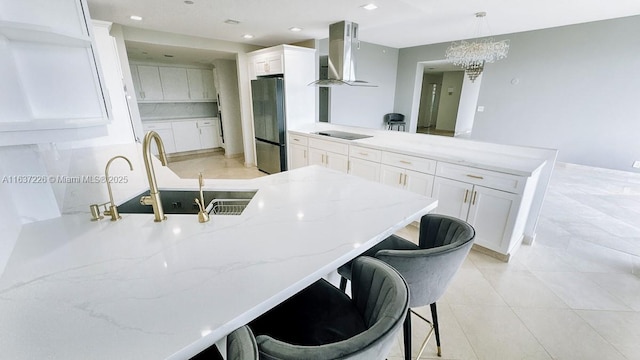 kitchen featuring white cabinets, hanging light fixtures, extractor fan, and stainless steel refrigerator