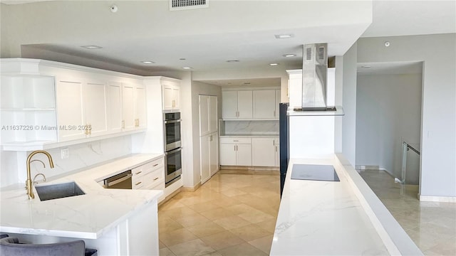 kitchen with light stone counters, extractor fan, a kitchen bar, white cabinets, and sink