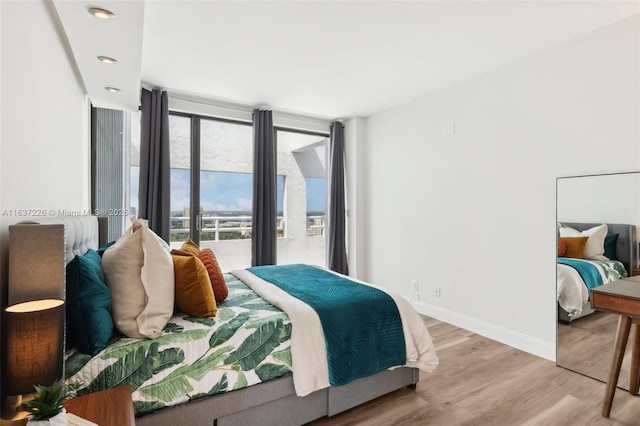 bedroom with a wall of windows and light wood-type flooring