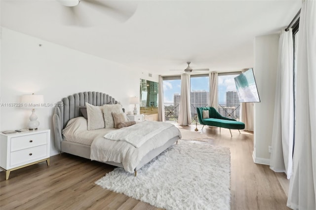 bedroom featuring ceiling fan, light hardwood / wood-style floors, and expansive windows