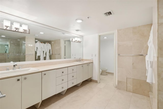 bathroom with toilet, vanity, and a shower with shower door