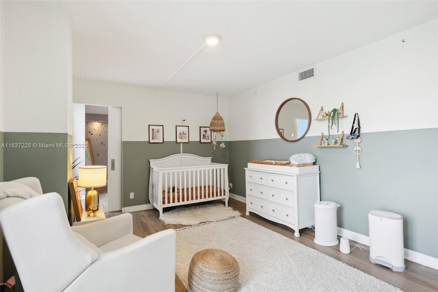 bedroom featuring a nursery area and hardwood / wood-style floors