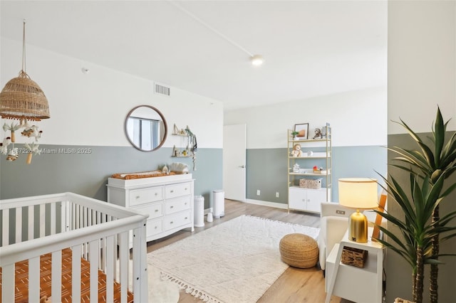 bedroom with a crib and light hardwood / wood-style flooring