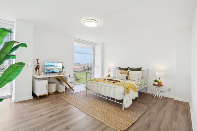 bedroom with access to exterior, floor to ceiling windows, and light hardwood / wood-style flooring