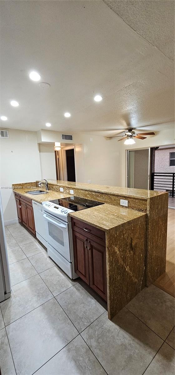 kitchen with white appliances, sink, light tile patterned floors, light stone countertops, and ceiling fan