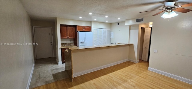 kitchen with light wood-type flooring, white refrigerator with ice dispenser, ceiling fan, and kitchen peninsula