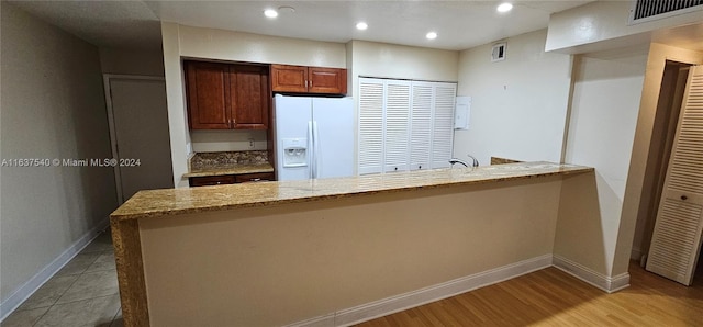 kitchen with white refrigerator with ice dispenser, baseboards, visible vents, light stone counters, and recessed lighting