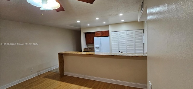 kitchen featuring ceiling fan, kitchen peninsula, light hardwood / wood-style flooring, and white fridge with ice dispenser