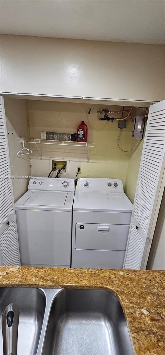 washroom featuring laundry area, washer and clothes dryer, and a sink