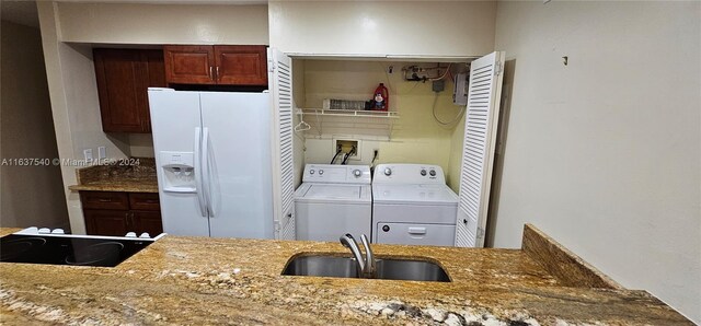 kitchen with black electric cooktop, white fridge with ice dispenser, washer and clothes dryer, sink, and light stone countertops