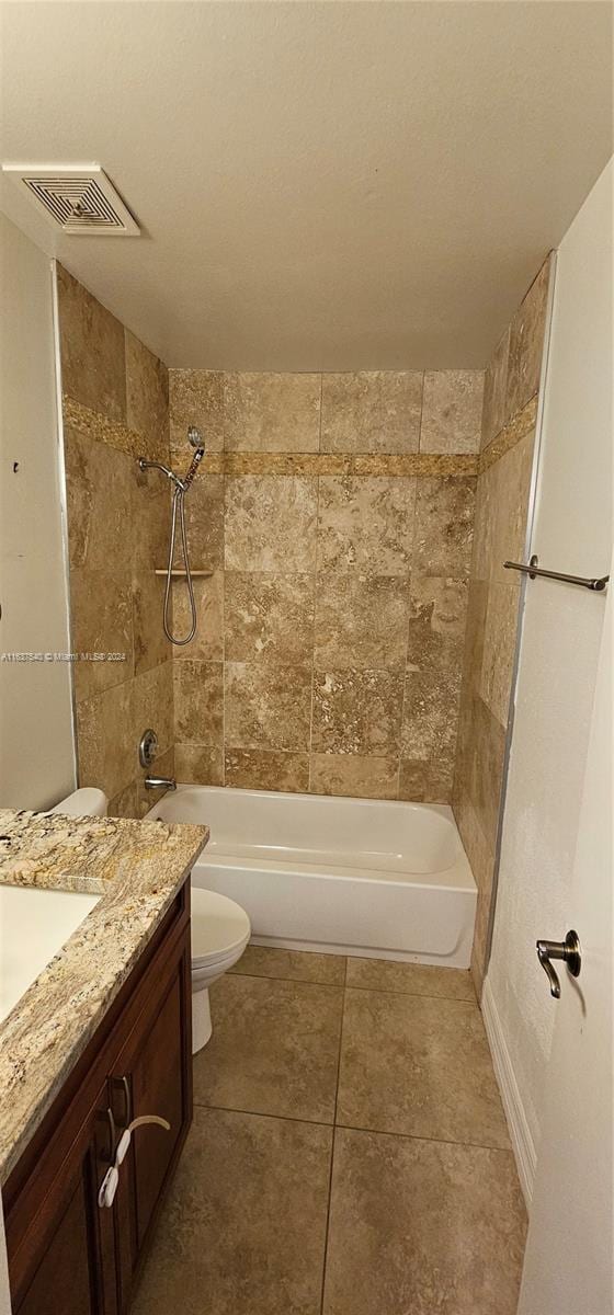 full bathroom with tile patterned floors, vanity, tiled shower / bath combo, and toilet