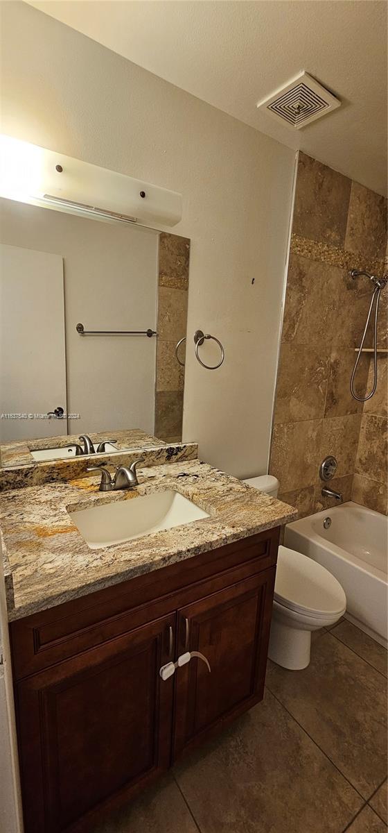 full bath with toilet, bathing tub / shower combination, tile patterned flooring, and visible vents