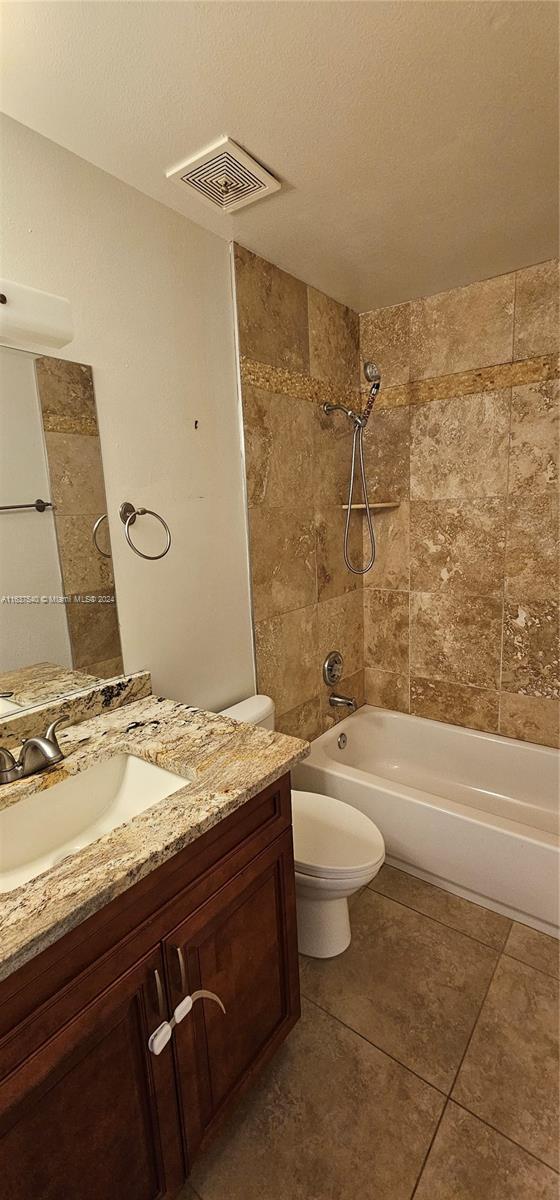 bathroom with bathing tub / shower combination, visible vents, toilet, vanity, and tile patterned floors