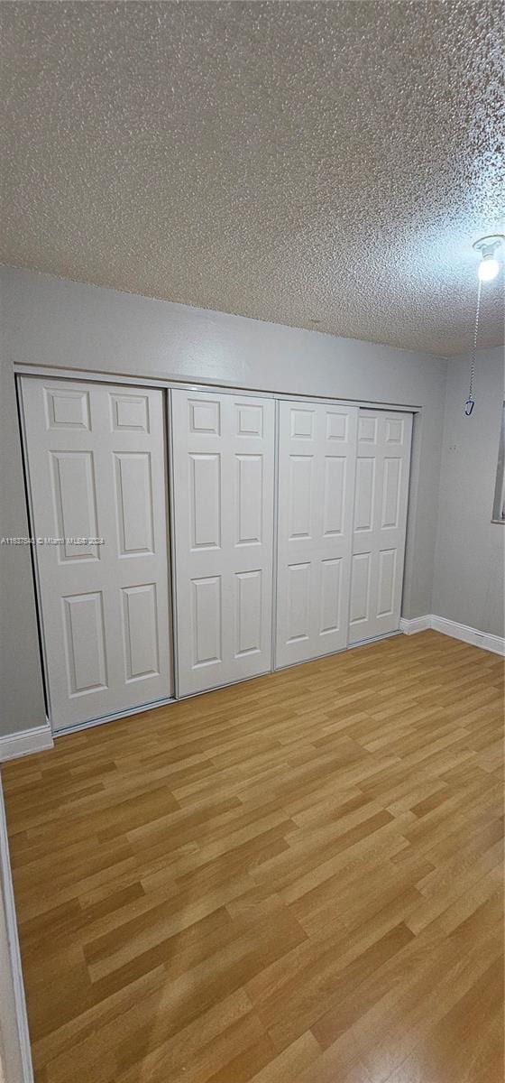 unfurnished bedroom with a textured ceiling and light hardwood / wood-style flooring