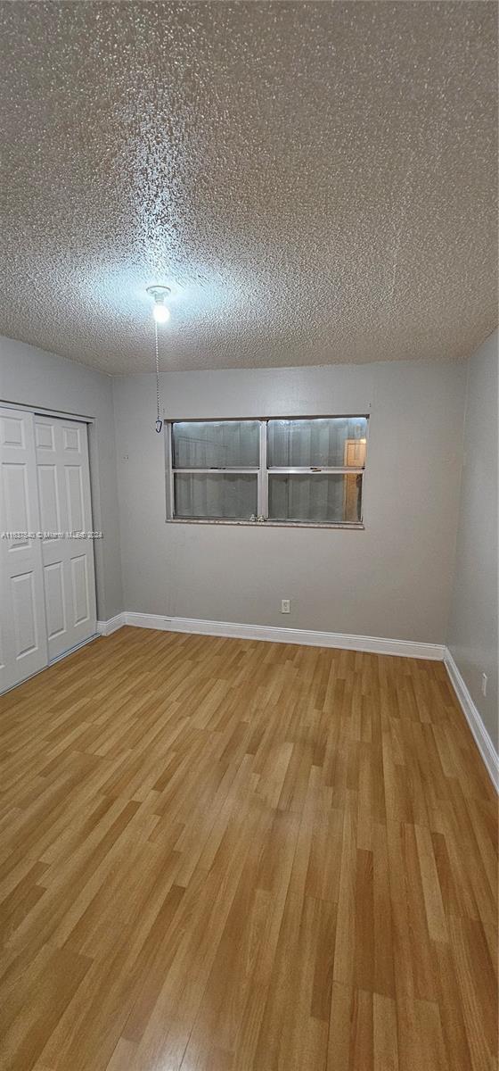 interior space with a textured ceiling, wood finished floors, and baseboards