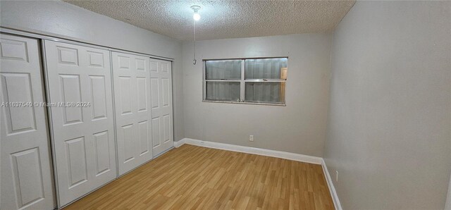 unfurnished bedroom featuring a closet, a textured ceiling, and light wood-type flooring