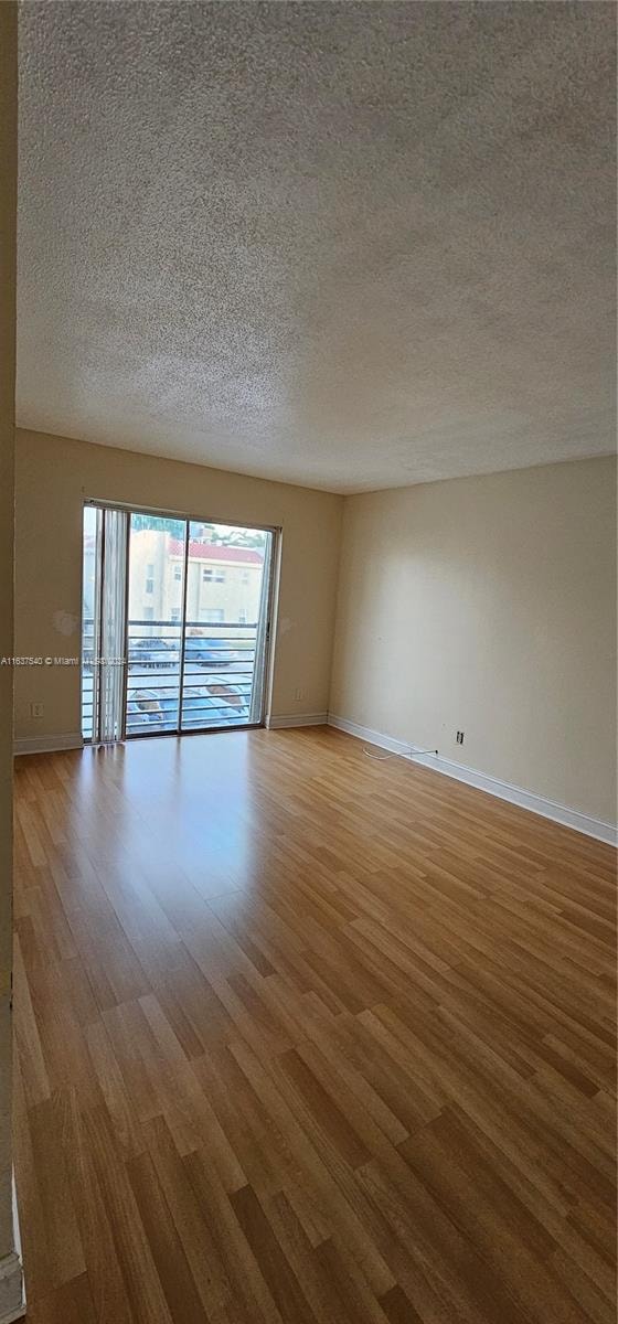 unfurnished room with hardwood / wood-style floors and a textured ceiling