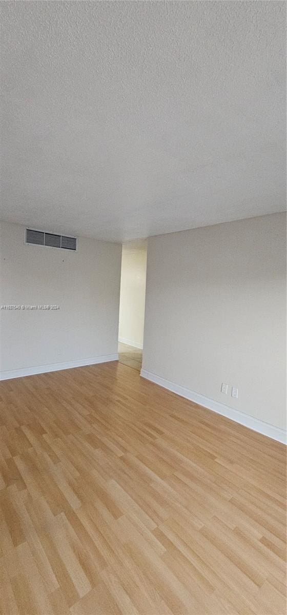 empty room featuring light hardwood / wood-style flooring and a textured ceiling