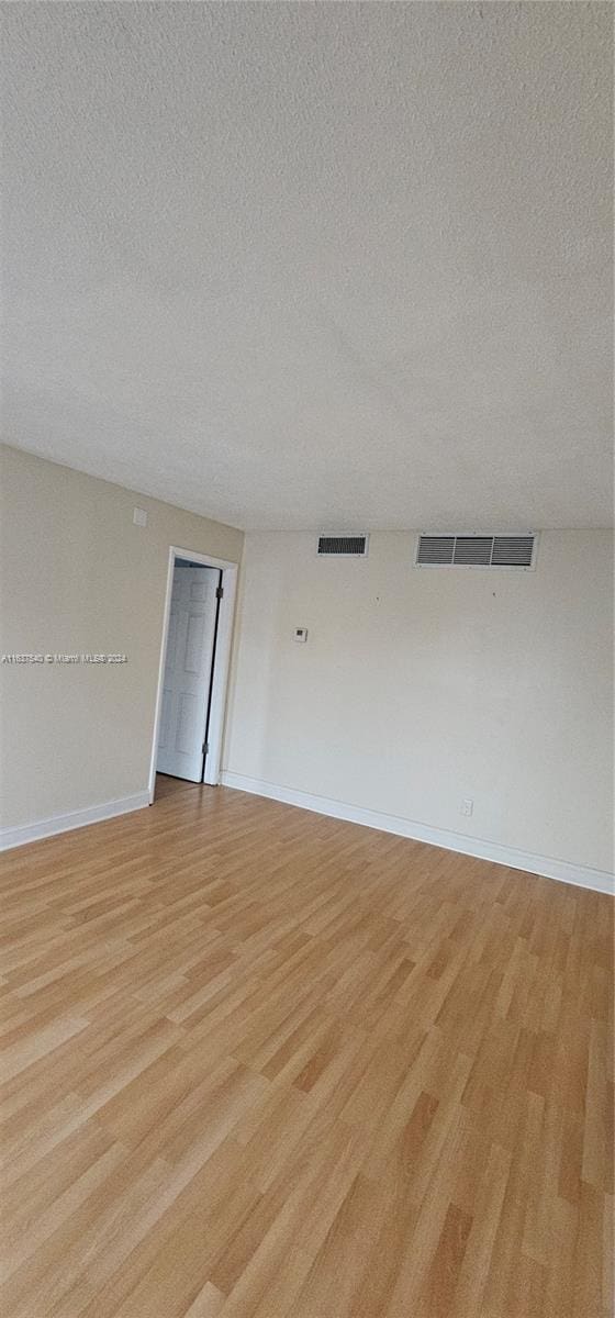 unfurnished room with light wood-style floors, baseboards, and visible vents