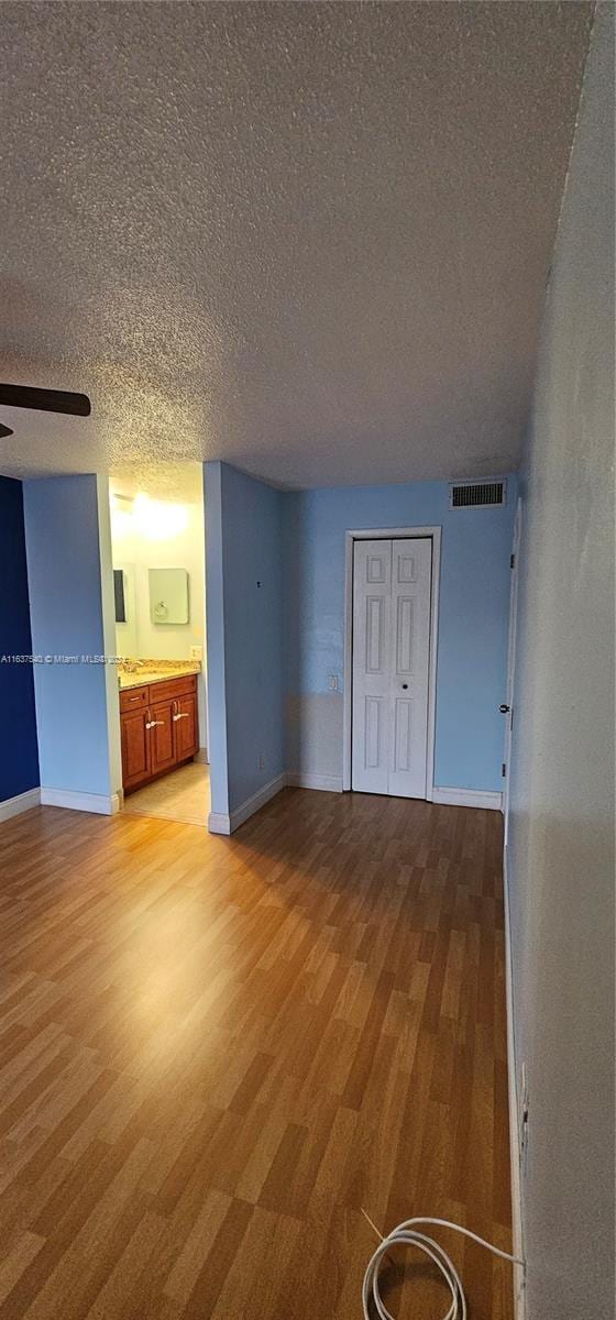 unfurnished bedroom with baseboards, visible vents, light wood-style flooring, and a textured ceiling