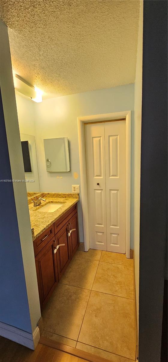 bathroom with a textured ceiling, tile patterned flooring, and vanity