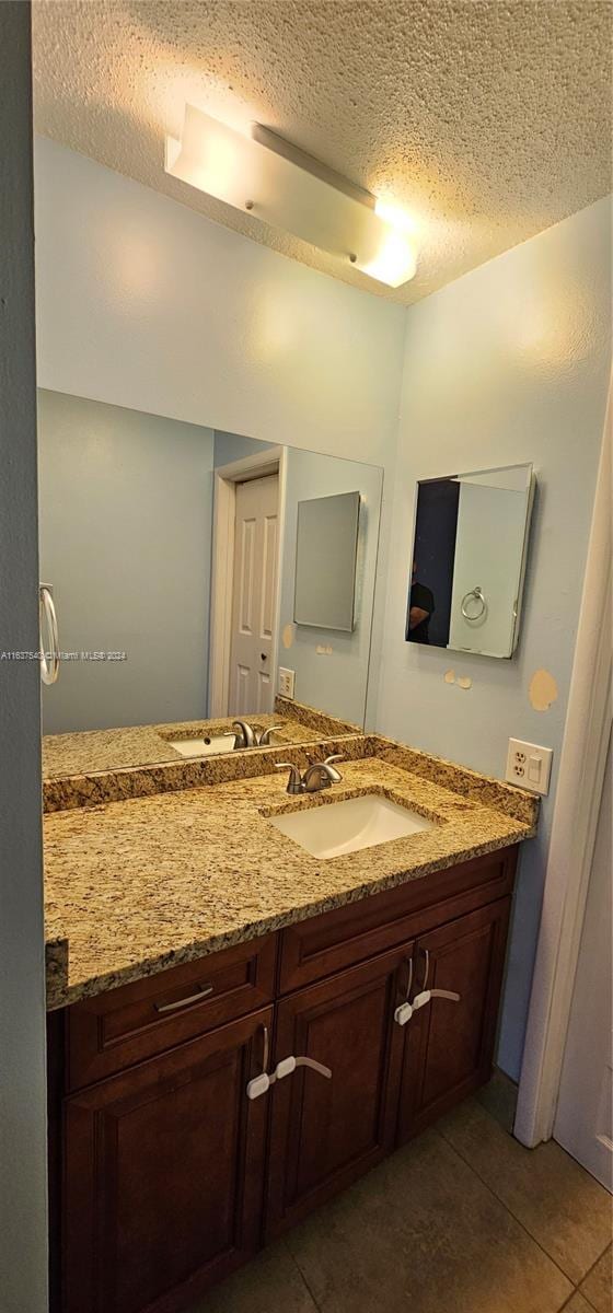 bathroom featuring tile patterned flooring, vanity, and a textured ceiling