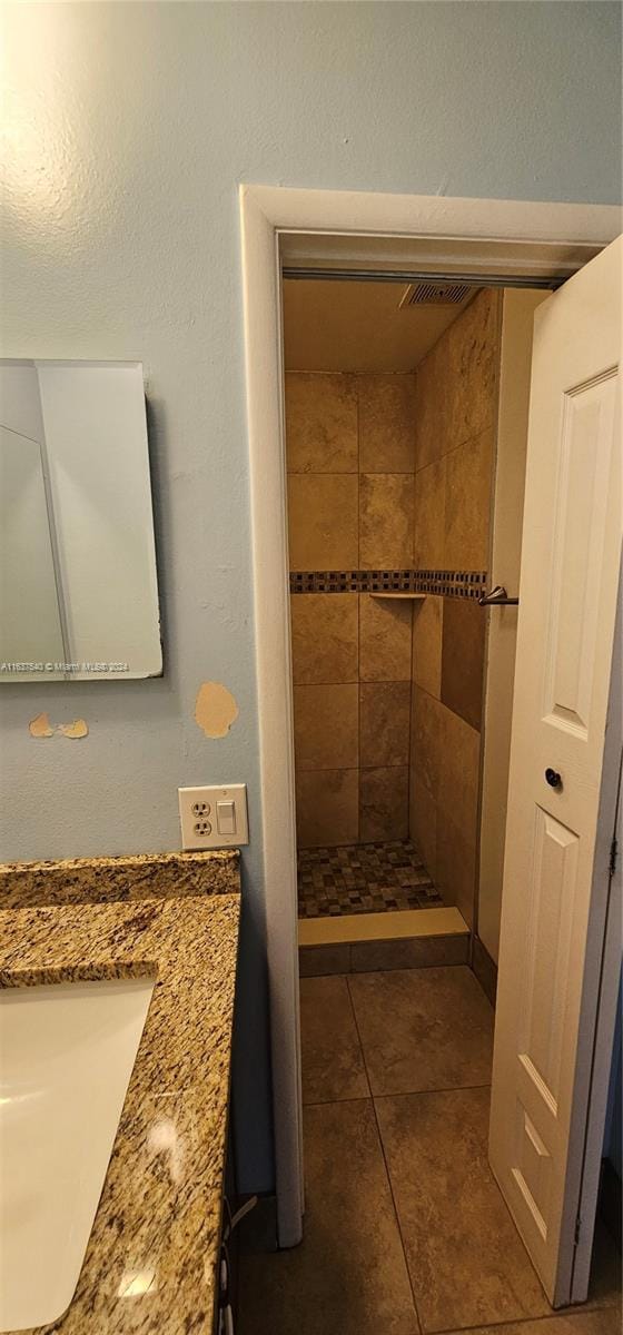 bathroom featuring tiled shower, vanity, and tile patterned floors