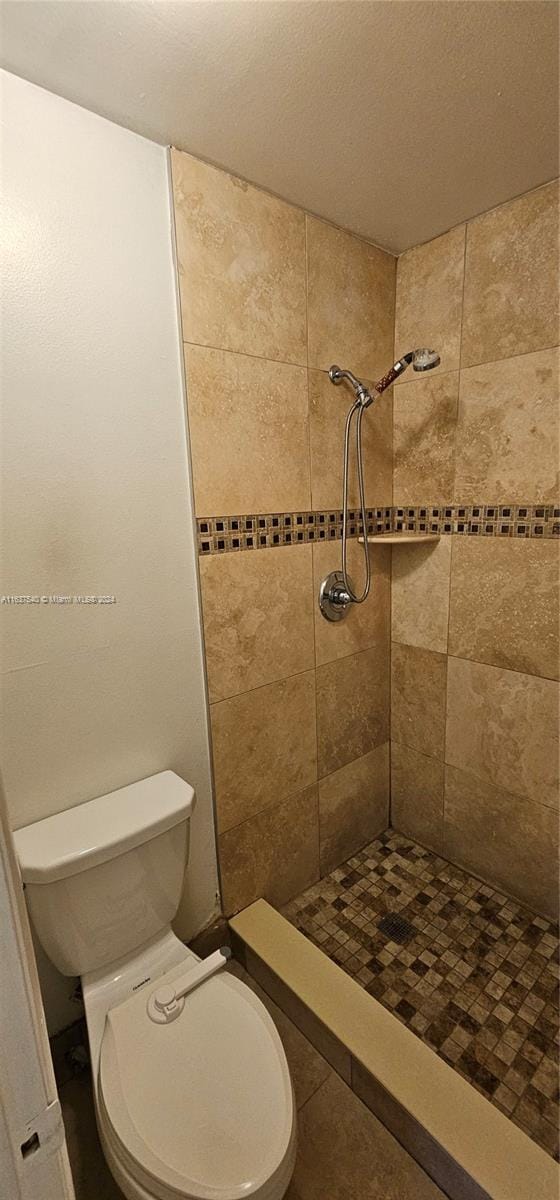 full bathroom with tiled shower and toilet