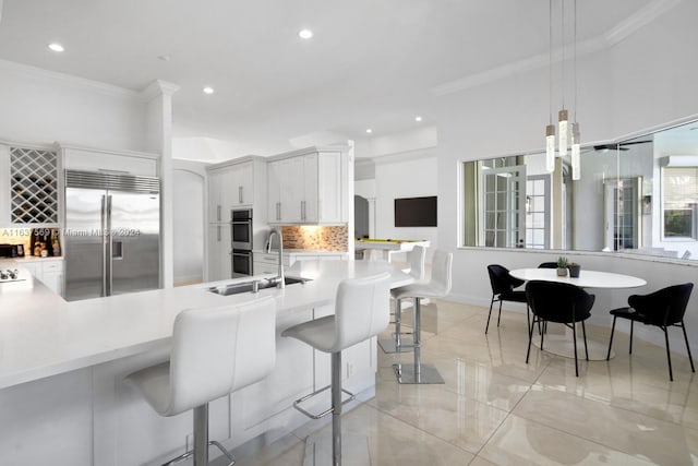 kitchen featuring a breakfast bar, decorative light fixtures, stainless steel appliances, light countertops, and ornamental molding