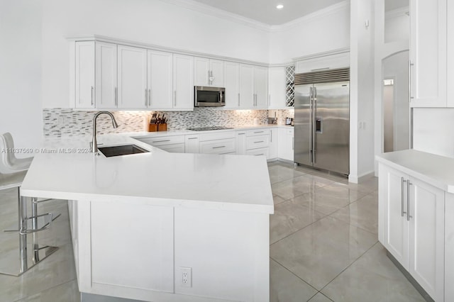 kitchen featuring tasteful backsplash, white cabinets, appliances with stainless steel finishes, ornamental molding, and a sink