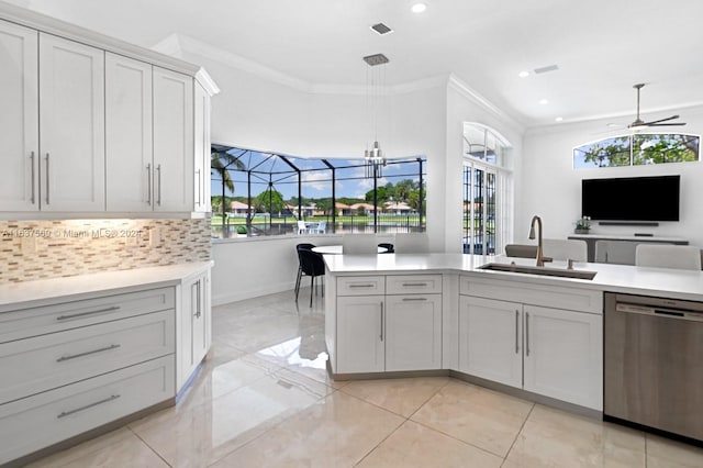 kitchen featuring decorative light fixtures, light countertops, stainless steel dishwasher, white cabinetry, and a sink