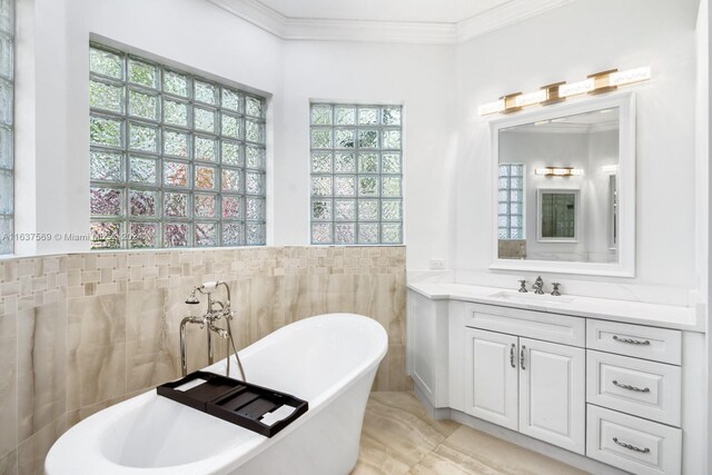 bathroom with tile walls, tile patterned flooring, crown molding, vanity, and a bath