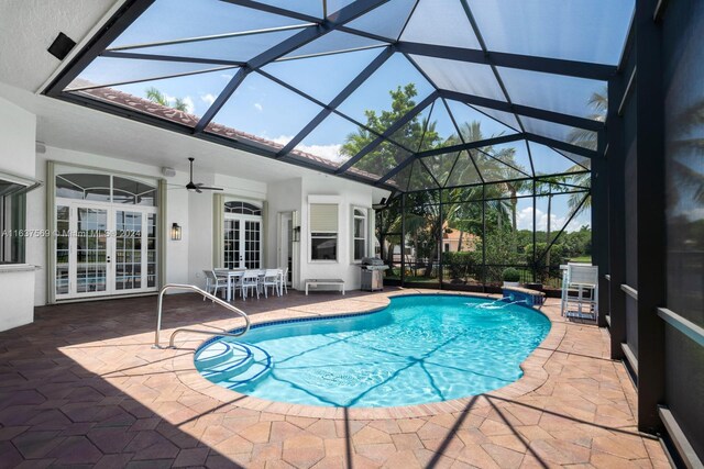 view of pool with pool water feature, french doors, a patio area, ceiling fan, and glass enclosure