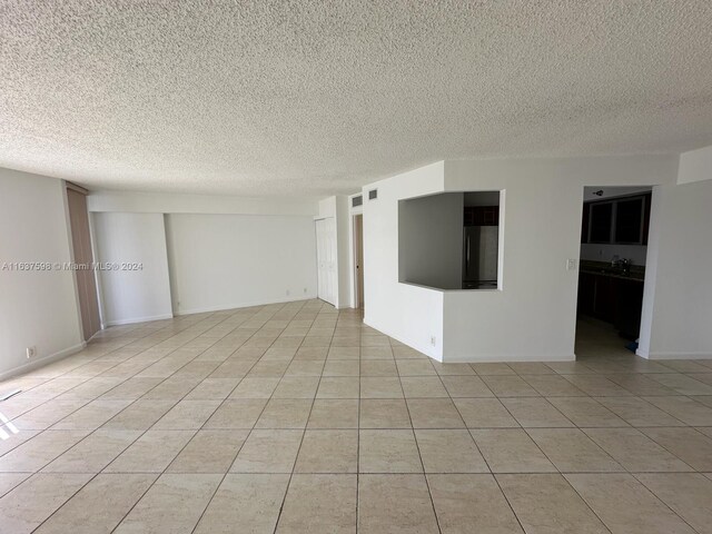 empty room featuring a textured ceiling and light tile patterned floors