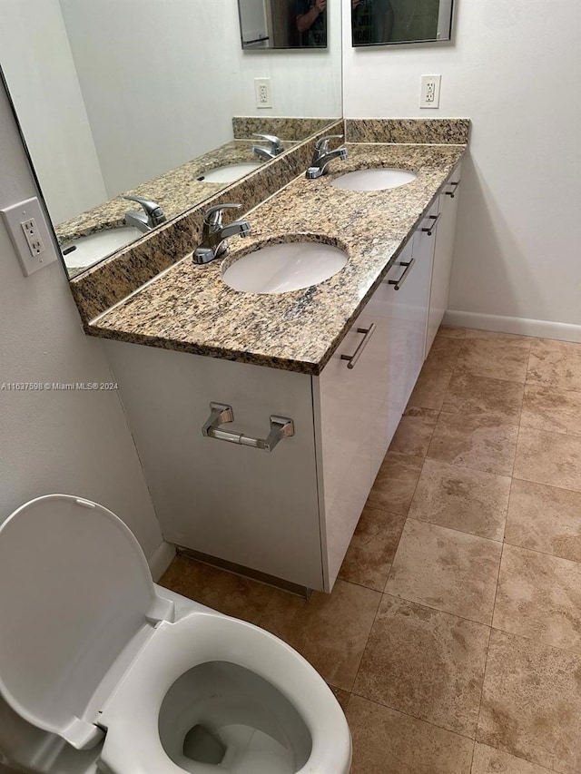 bathroom featuring double vanity, toilet, and baseboards