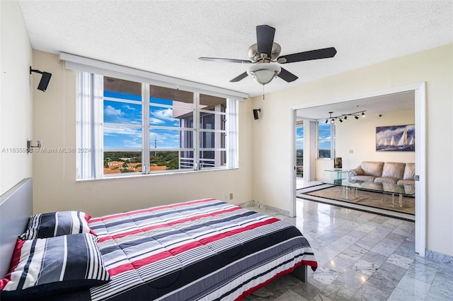 bedroom with a textured ceiling, rail lighting, and ceiling fan