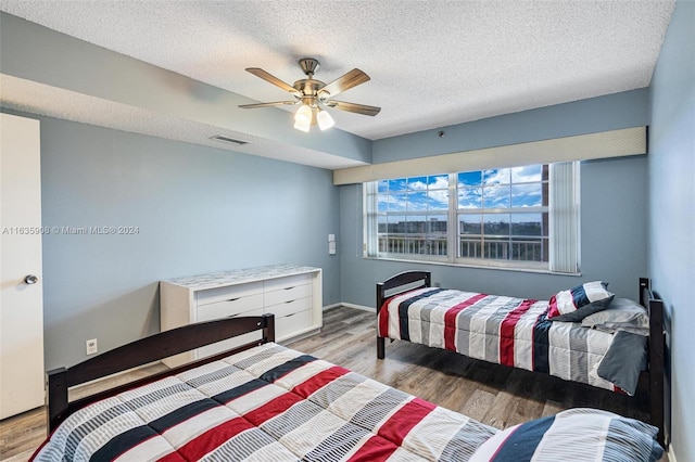 bedroom with light wood-type flooring, a textured ceiling, and ceiling fan