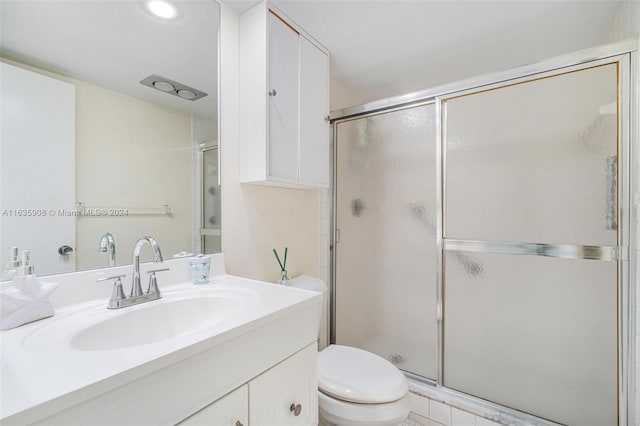 bathroom with vanity, toilet, and a shower with door