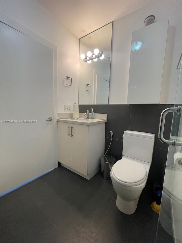 bathroom featuring tile walls, tile patterned floors, toilet, and vanity