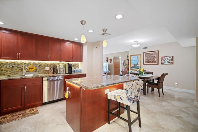 kitchen with light stone counters, pendant lighting, a kitchen island, and stainless steel dishwasher