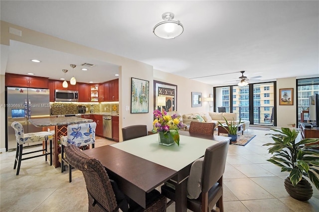 tiled dining area with floor to ceiling windows and ceiling fan