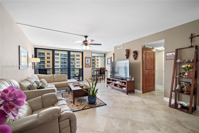 living room featuring a barn door, light tile patterned floors, ceiling fan, and expansive windows