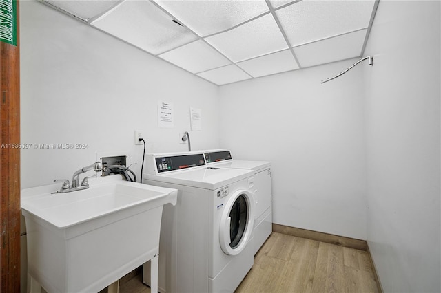 washroom featuring light wood-type flooring, washer and clothes dryer, and sink