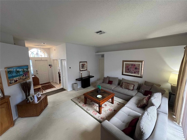 living room with a textured ceiling, visible vents, and light carpet