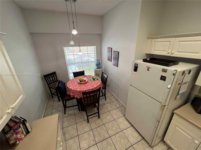dining space with light tile patterned floors, a textured ceiling, lofted ceiling, and baseboards