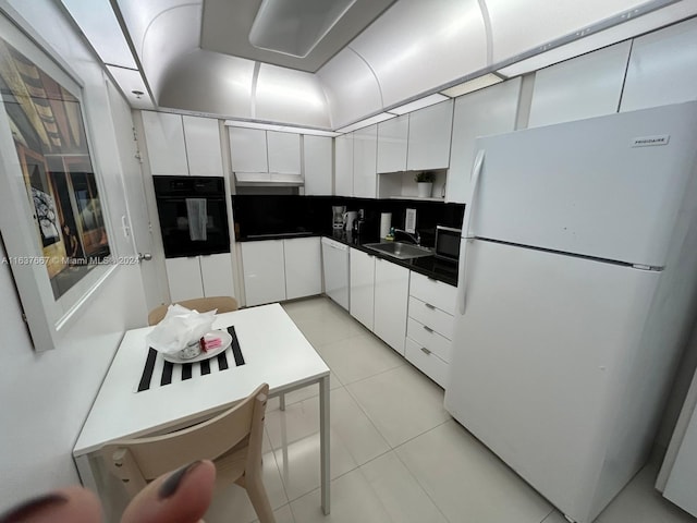 kitchen with white cabinetry, sink, white appliances, and light tile patterned floors