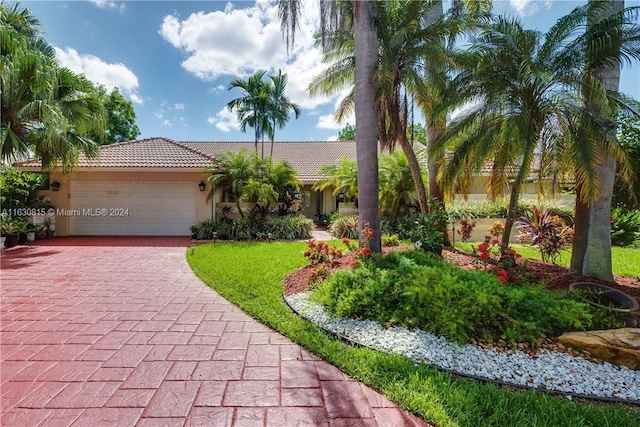 view of front facade featuring a tiled roof, decorative driveway, an attached garage, and stucco siding