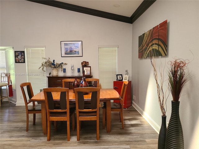 dining space with crown molding, vaulted ceiling, and hardwood / wood-style floors