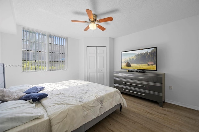 bedroom with ceiling fan, a closet, a textured ceiling, and hardwood / wood-style floors