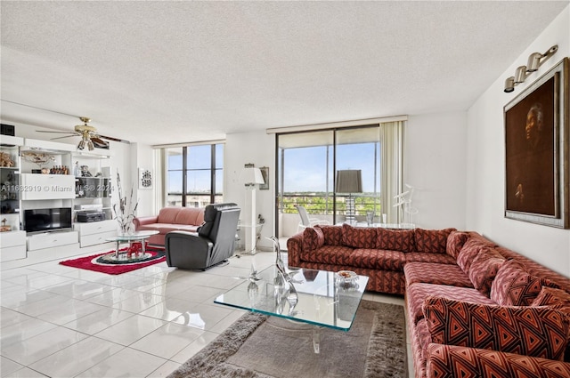 tiled living room with a textured ceiling, ceiling fan, and a wall of windows